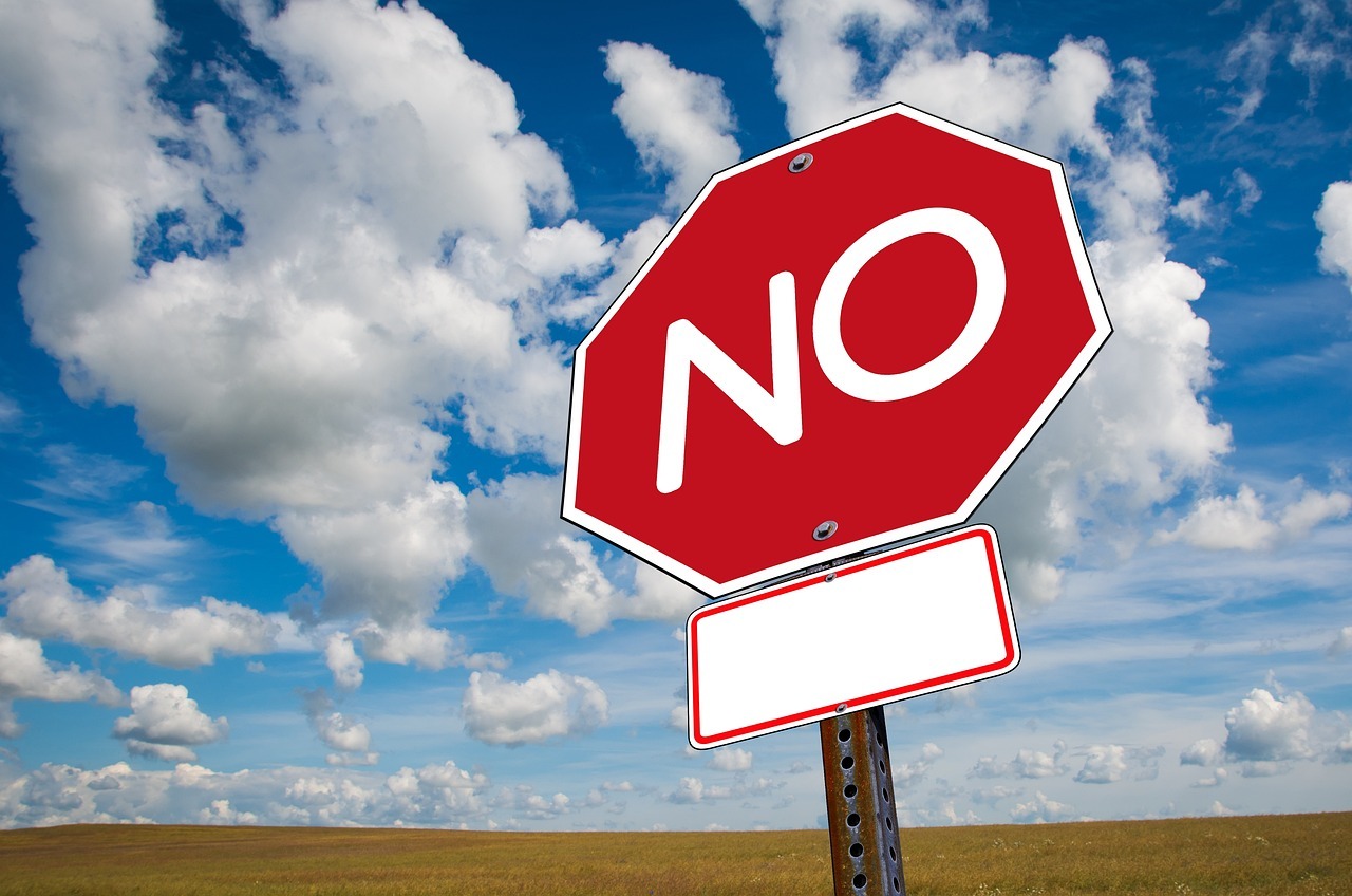 stop sign with the word "no" instead of "stop" in front of a blue sky with clouds background.